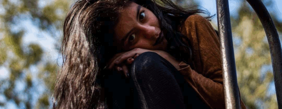 young woman leaning against the rungs at the top of metal steps. Her head is tilted and she is looking forward with dark eyes. This phot is used in a post on www.becomingstoic.net called "Dealing with Jerks".